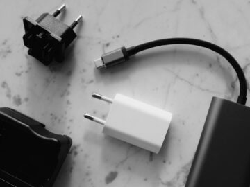 Composition of various modern charging units with adapter and small black external battery with short cable placed on white marble table