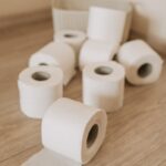 Multiple toilet paper rolls scattered on a wooden floor, highlighting hygiene essentials.