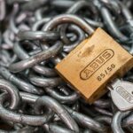 A detailed macro shot of a brass padlock with a key on heavy steel chains, symbolizing security and protection.