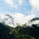 a mountain range covered in clouds and trees