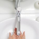 Hands washing under a sleek faucet with water flowing in a white basin