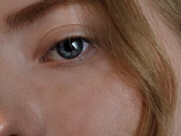 Intimate close-up of a woman's blue eye with blonde hair, capturing natural beauty.
