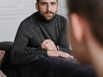 A thoughtful therapist listens attentively to a patient during a counseling session in a modern office.