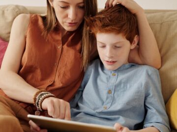A mother and son bonding as they use a tablet together indoors.