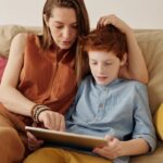 A mother and son bonding as they use a tablet together indoors.
