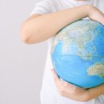 Child holding a globe against a white background, symbolizing global connection and unity.
