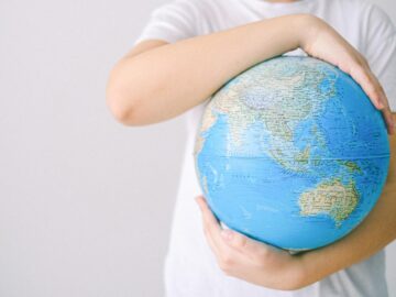 Child holding a globe against a white background, symbolizing global connection and unity.