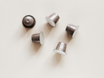 Minimalist photograph of several silver coffee capsules on a light background, perfect for coffee-related projects.