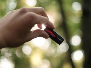 Close-up of a hand holding a USB drive outdoors with a bokeh background.