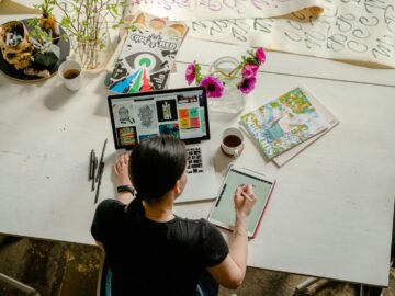 Artistic workspace featuring calligraphy and digital design on a tablet and laptop.