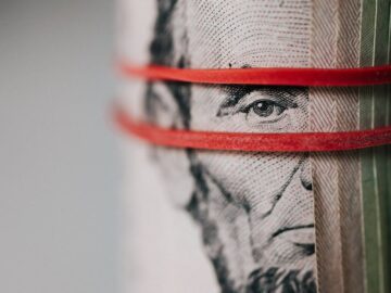 Closeup of rolled United States five dollar bills tightened with red rubber band