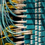 Blue and yellow optical fiber cables connected to ports in a server room.