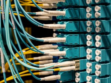 Blue and yellow optical fiber cables connected to ports in a server room.