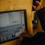 Close-up of a person using a ticket machine for Berlin's U-Bahn public transport in evening light.