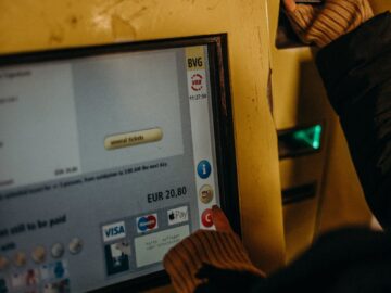 Close-up of a person using a ticket machine for Berlin's U-Bahn public transport in evening light.