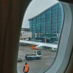 Working vehicle and unrecognizable person in uniform from small oval window of aircraft