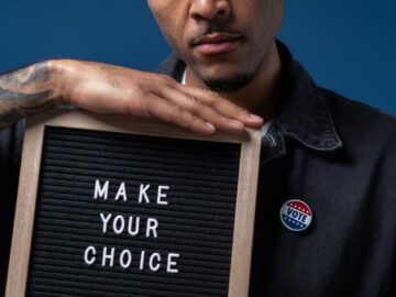Serious man with 'make your choice' sign highlights the importance of voting and civic duty.