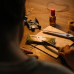 Person soldering a printed circuit board at a workstation with tools and components.
