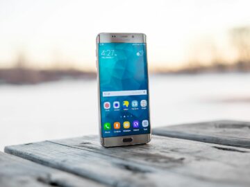 Samsung smartphone placed on a wooden surface outdoors during sunset.