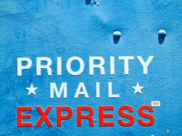 Close-up of a blue USPS mailbox featuring 'Priority Mail Express' text, ideal for postal themes.