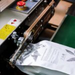 Close-up of a coffee bag being sealed by an industrial machine, showcasing manufacturing precision.
