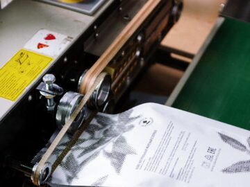 Close-up of a coffee bag being sealed by an industrial machine, showcasing manufacturing precision.