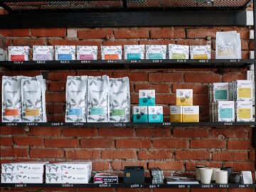 Brick wall shelving in a café with various coffee products and modern decor.
