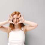 A young woman with red hair poses with 'No' and 'Yes' written on her palms, showcasing consent.