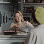 A cheerful female clerk helps a customer at a cozy bookstore counter.