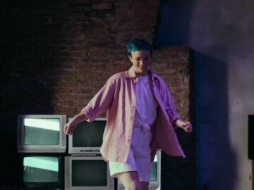 Teen girl with colored hair roller skating indoors near old CRT TVs, exuding fun and retro vibes.