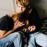 Two women sharing a comforting moment on a kitchen floor, depicting empathy and support.