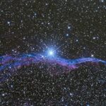 Vibrant image of the Veil Nebula, a supernova remnant in space, with a star-filled background.