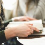 woman sitting on chair in front of table white reading book