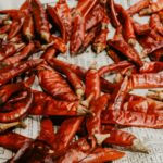 A vibrant display of dried red chili peppers spread out on a newspaper surface.