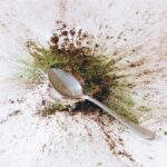 A spoon surrounded by a colorful burst of spices on a white background, creating an abstract splash.