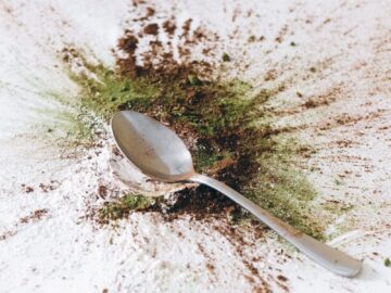 A spoon surrounded by a colorful burst of spices on a white background, creating an abstract splash.