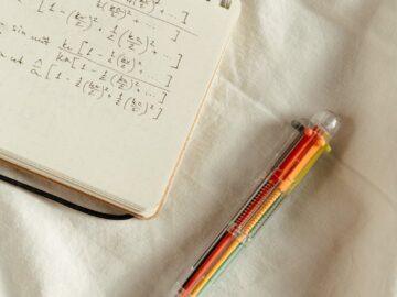 Handwritten math formulas on a notepad with a colorful pen on a white background.