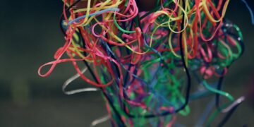 A hand holding a tangle of colorful rubber bands symbolizing chaos and creativity.
