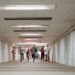 A diverse group of friends joyfully running through a modern, urban underpass creating a vibrant scene.