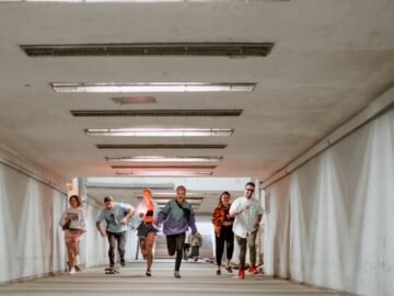 A diverse group of friends joyfully running through a modern, urban underpass creating a vibrant scene.