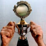 Close-up of hands holding a shiny trophy symbolizing achievement and victory.