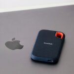 Close-up of a portable SanDisk external hard drive resting on a laptop surface, highlighting modern data storage solutions.