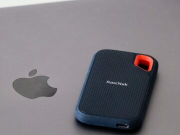 Close-up of a portable SanDisk external hard drive resting on a laptop surface, highlighting modern data storage solutions.