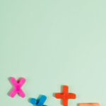 Bright plastic math symbols for arithmetic on a pastel green background with copy space.