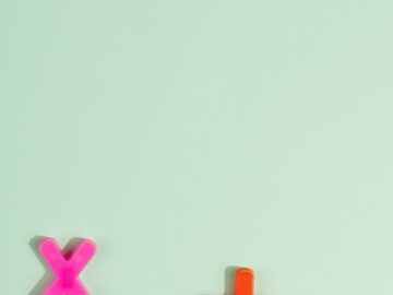 Bright plastic math symbols for arithmetic on a pastel green background with copy space.