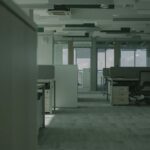Spacious empty office featuring modern desks, chairs, and partitions.
