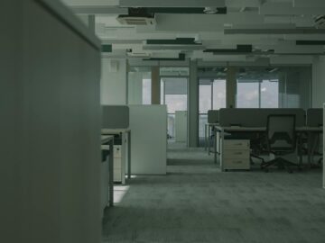 Spacious empty office featuring modern desks, chairs, and partitions.