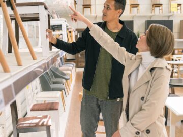 A couple shopping for furniture in a brightly lit store, discussing options.