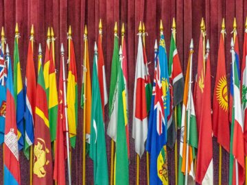 A vibrant collection of diverse national flags arrayed indoors on flagpoles.