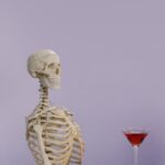 Skeleton model with a cocktail glass on a purple background, playful and intriguing vibe.